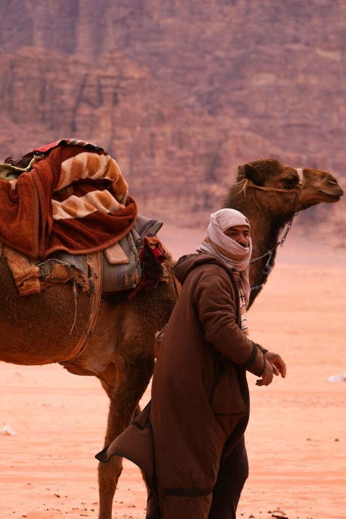 A Bedouin man leads a camel through the stunning desert landscape of Aqaba, Jordan.